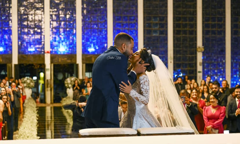 Intimate altar kiss from different angle showing full ceremony setting with blue windows