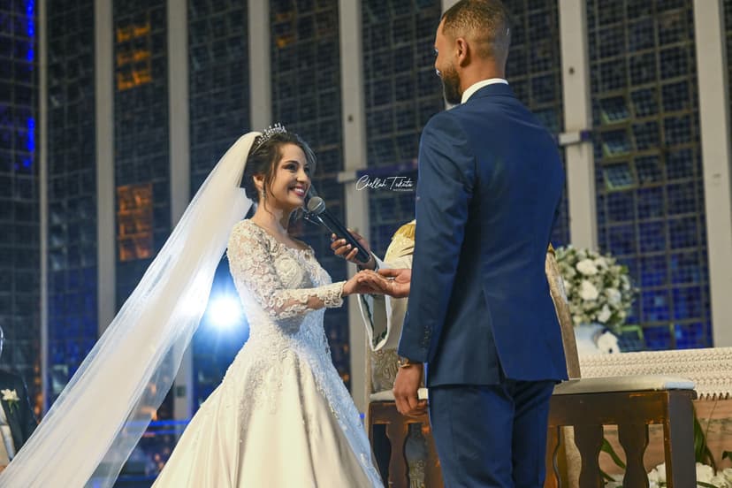 Bride speaking wedding vows into microphone, smiling at groom during ceremony