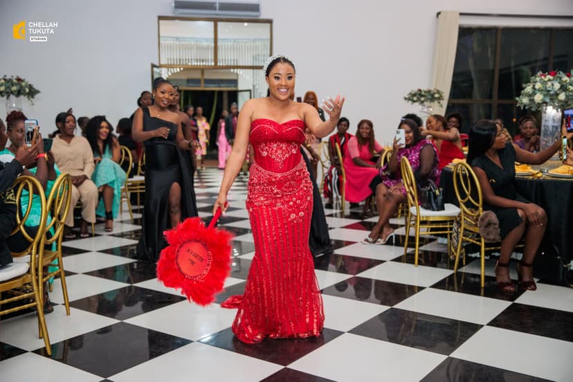 Bride in red reception dress waving with red feather fan