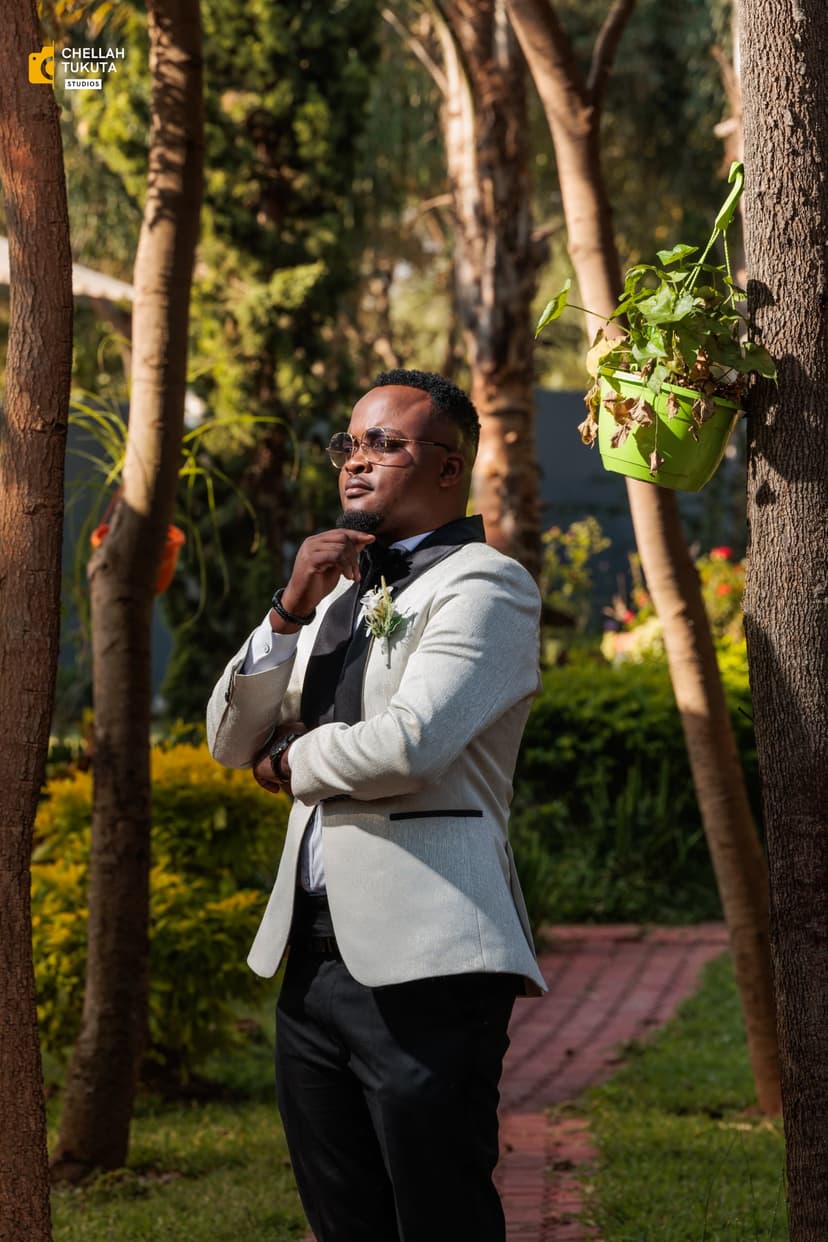 Candid groom moment adjusting bow tie in natural garden setting