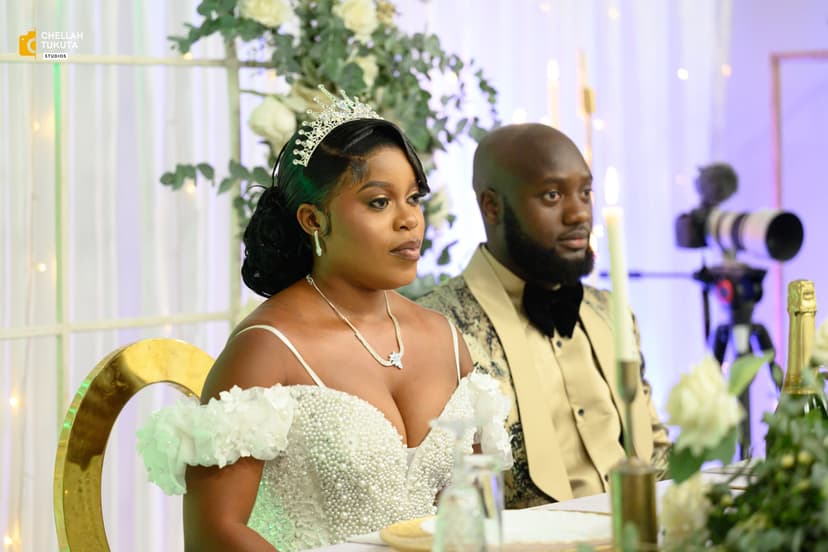 Elegant couple at reception - bride in white beaded dress with crown, groom in gold suit