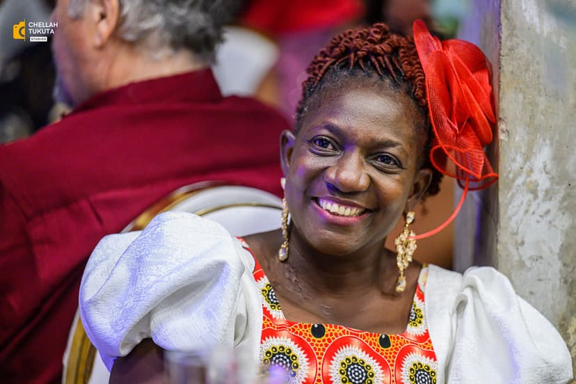Joyful wedding guest in traditional white outfit with red fascinator