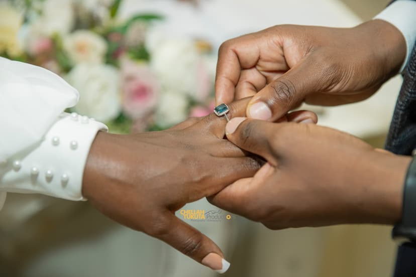 Ring exchange ceremony with emerald ring and floral background