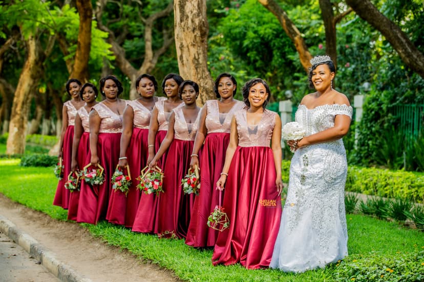 Final bridal party lineup - bride with tiara and bridesmaids in burgundy holding bouquets
