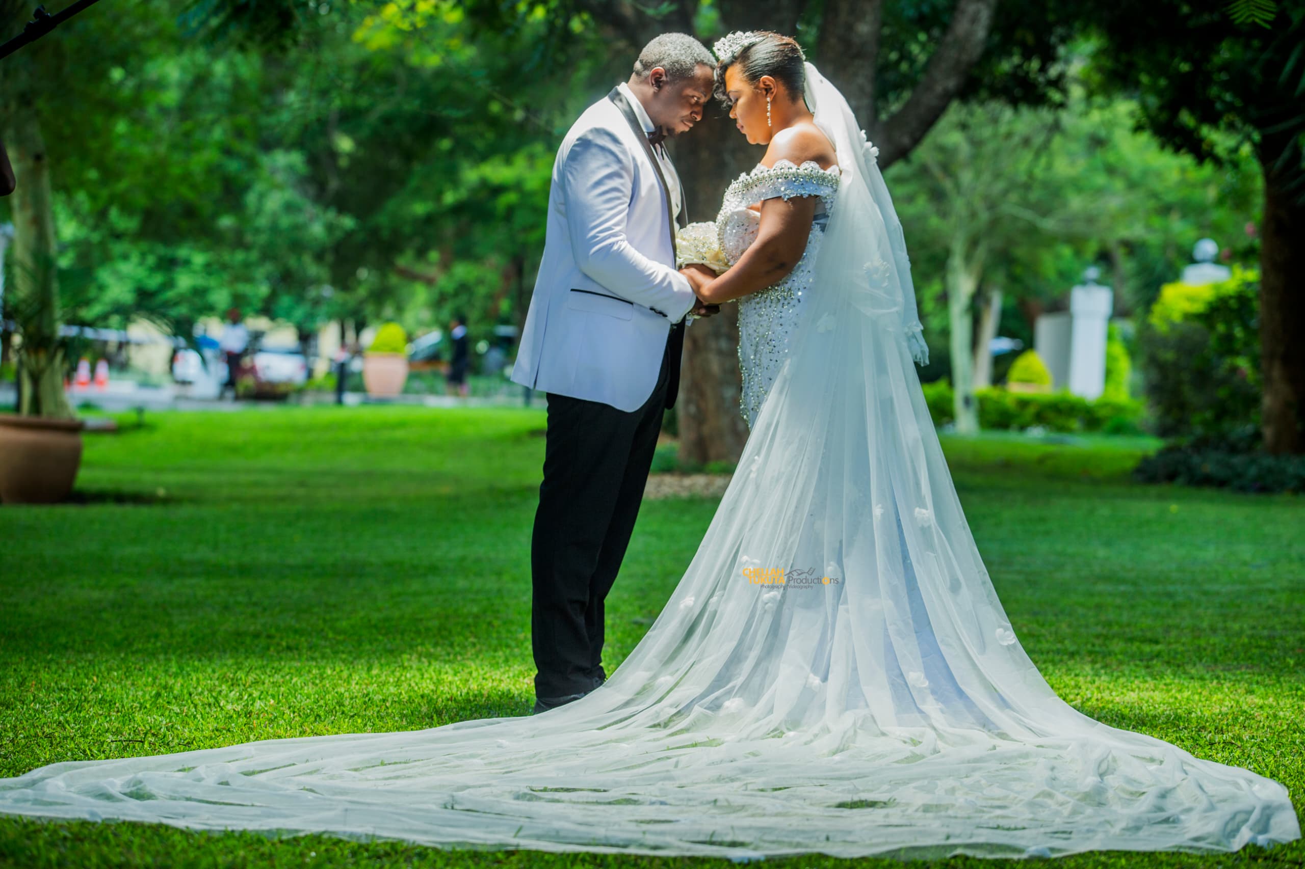 Intimate romantic moment - couple forehead to forehead with flowing veil in park setting